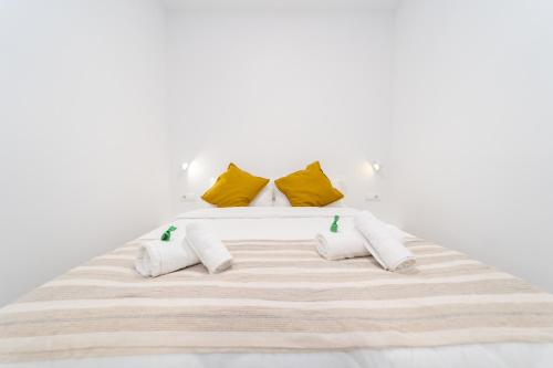 a white bed with yellow pillows on it at Ca la Mar Villajoyosa in Villajoyosa