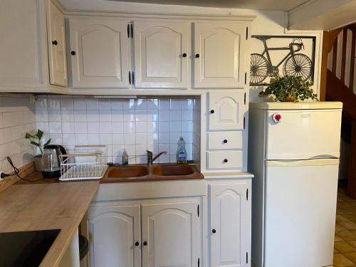 une cuisine avec des armoires blanches, un évier et un réfrigérateur dans l'établissement Baya, à La Chapelle-Saint-André