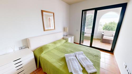 1 dormitorio con cama verde y ventana grande en Orquidea, en Perelló