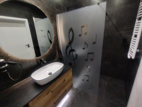 a bathroom with a sink and a mirror with music notes on the wall at Apartament,,Nuta'' in Gniezno