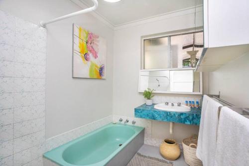 a bathroom with a blue tub and a sink at Vivid house in Wembley Downs in Perth