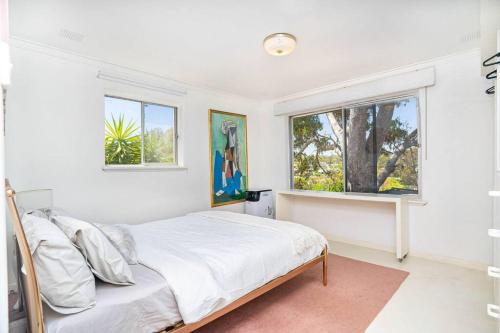 a white bedroom with a bed and two windows at Vivid house in Wembley Downs in Perth