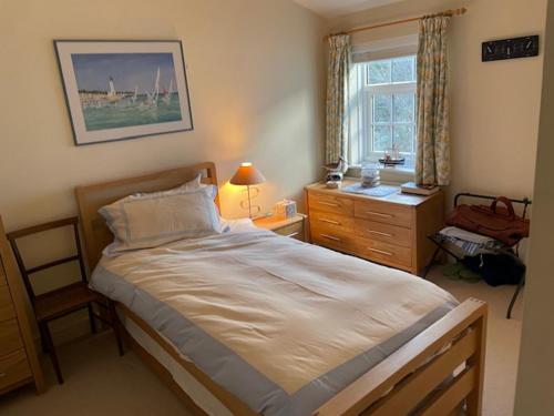 a bedroom with a bed and a dresser and a window at The Old Coach House in Cheltenham