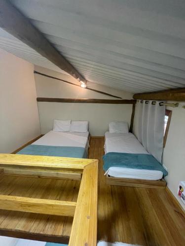 two beds in a small room with wooden floors at Pousada Dona Carmem Ubatuba in Ubatuba