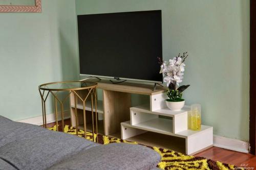 un soggiorno con TV su un tavolo di Sunflower Cottage 15min from OR Tambo a Johannesburg