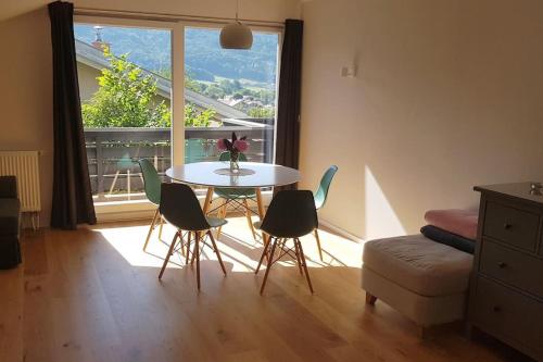 een tafel en stoelen in een kamer met een raam bij Moderne Ferienwohnung mit großem Balkon in Aschau im Chiemgau
