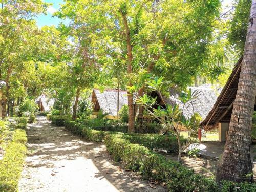 a path through a forest with trees and houses at Sulu Sunset Beach Resort in Nauhang