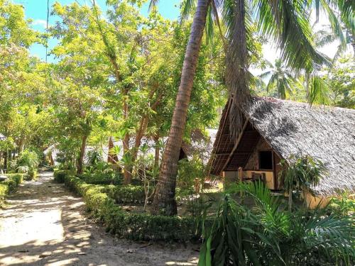 a resort with a thatched building and palm trees at Sulu Sunset Beach Resort in Nauhang