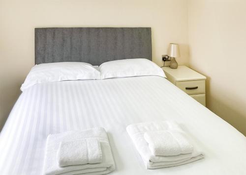 a large white bed with two white towels on it at Whitecairn Holiday Park in Glenluce