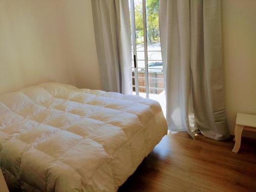 a bed in a room with a large window at Amplio dúplex en Lomas con cochera in Lomas de Zamora