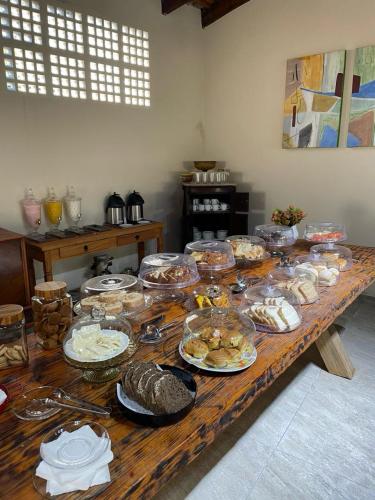 a long wooden table with many plates of food on it at Pousada Dona Carmem Ubatuba in Ubatuba