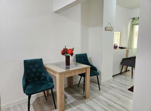 einen Esstisch mit grünen Stühlen und eine Vase mit Blumen in der Unterkunft Apartman NENA 102 in Mostar