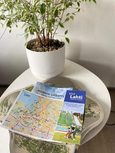 a plate with a book and a potted plant on a table at VesiLahti RoofLevel Apartment in Lahti