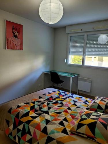 ein Schlafzimmer mit einem Bett mit einer bunten Bettdecke in der Unterkunft T3 proche bus et tram in Angers