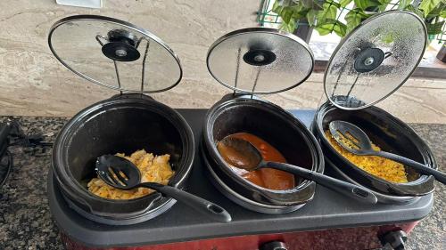 three pots of food on a table with spoons at Hotel Olho D'água - Baturité in Baturité