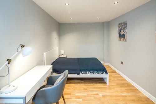 ein weißes Schlafzimmer mit einem Bett und einem Schreibtisch in der Unterkunft Cosy 2-Beds, Shepherd Bush in London