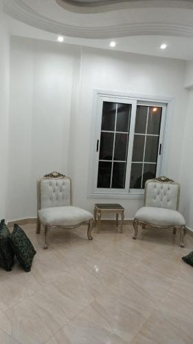 2 stoelen en een tafel in een kamer met een raam bij Nargesstar in Caïro