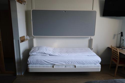 a bed in a room with a board on the wall at Hesehotelli Turku Linja-autoasema in Turku