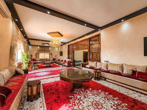 ein großes Wohnzimmer mit einem Sofa und einem Tisch in der Unterkunft Maison d'hôtes bon coin in Marrakesch