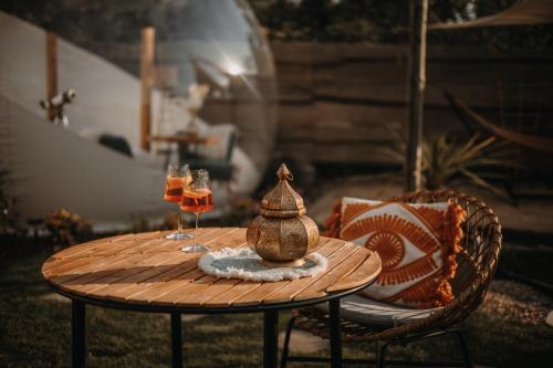 a wooden table with two glasses of wine on it at Alpacosi Oase - Schlafen unter den Sternen in Zehdenick