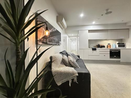 a living room with a couch and a plant at Penthouse Sky View Apartment CBD 2BR Apartment Balcony Spa Access Sleeps 6 in Adelaide