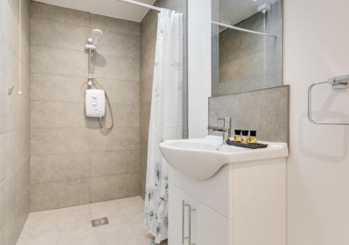 bagno bianco con lavandino e doccia di Ardley Cottages a Waldingfield