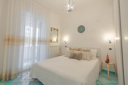 Maiori Apartment by Marcel في مايوري: غرفة نوم بيضاء بسرير ابيض وثريا