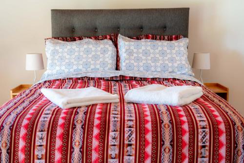 ein Bett mit zwei Kissen und einer roten Decke in der Unterkunft Huaraz Lodge and Bungalows in Huaraz