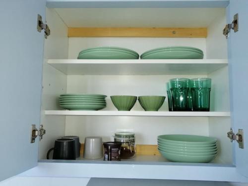 a cabinet filled with green plates and bowls at Aegina Port Apt 2-Διαμέρισμα στο λιμάνι της Αίγινας 2 in Aegina Town