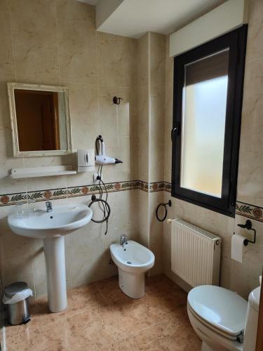 ein Badezimmer mit Waschbecken, Toilette und Fenster in der Unterkunft Hotel la Hoja*** in Aldeadávila de la Ribera