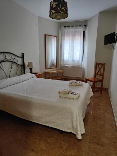 ein Schlafzimmer mit einem großen weißen Bett und einem Stuhl in der Unterkunft Hotel la Hoja*** in Aldeadávila de la Ribera