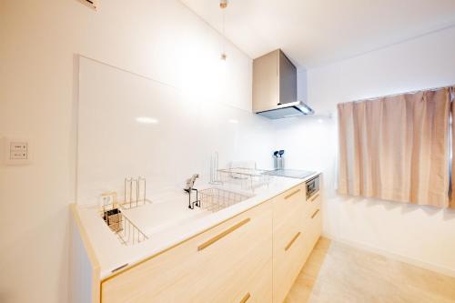 a kitchen with white walls and wooden cabinets at Furano Powder Chalet in Furano