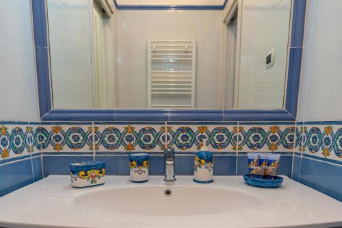 a bathroom sink with a mirror and blue and white tiles at Maiori Apartment by Marcel in Maiori