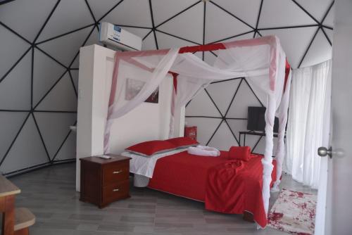 a bedroom with a red bed with a canopy at Eco Cabañas Montana in Santa Helena