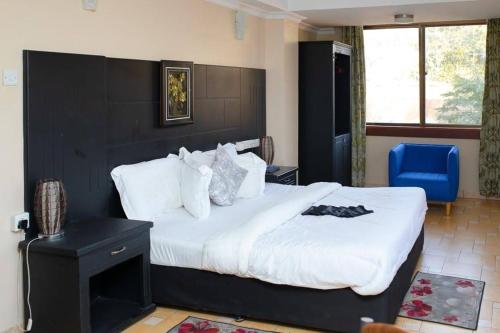 a bedroom with a large bed and a blue chair at Hotel Kingdom in Mwanza