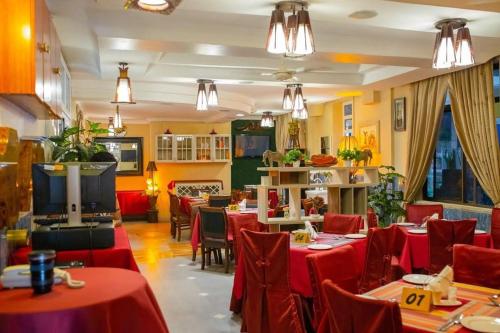 a restaurant with red tables and chairs and a tv at Hotel Kingdom in Mwanza