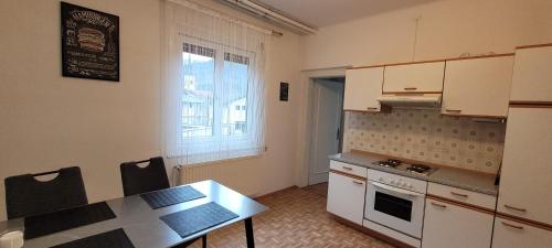 eine Küche mit weißen Schränken, einem Tisch und einem Fenster in der Unterkunft Appartement Huber - TOP1 in Bruck an der Mur