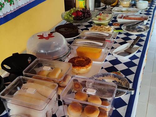 a table with many trays of food on it at Pousada Engenho Velho in Serra do Cipo