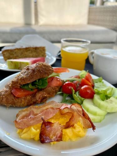 a plate of breakfast food with a sandwich and vegetables at Hotel Miramare Chioggia Sottomarina in Sottomarina