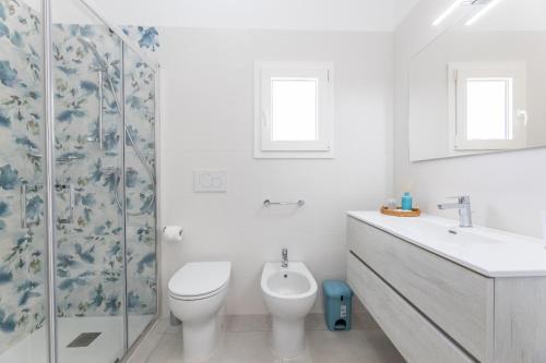 a white bathroom with a toilet and a sink at VILLA MARIA-TORRE SUDA in Torre Suda