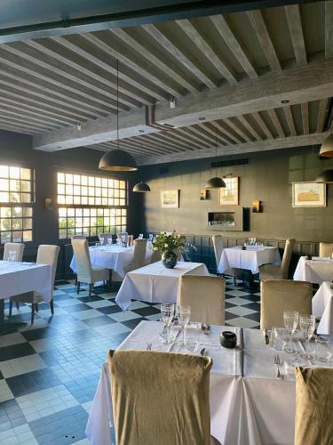 une salle à manger avec des tables et des chaises blanches dans l'établissement Hôtel de la Tour, à Châtillon-sur-Chalaronne