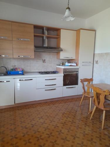 une cuisine avec des placards blancs, une table, une table et une chaise dans l'établissement Casa Rosanna, à Marina di Caulonia