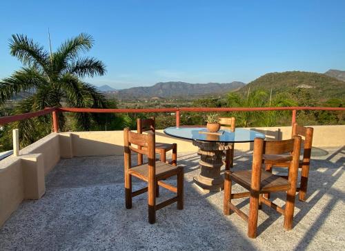 a patio with a table and chairs and a palm tree at Vistas a las Montañas y al Mar I Condominio Las Calandrias I Alberca I Wi-Fi in Ixtapa