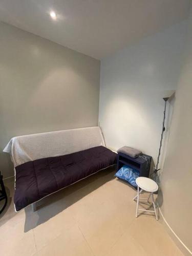 een kleine kamer met een bed, een kruk en een stoel bij studio 75012 in Parijs