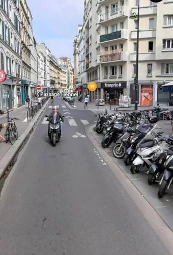 a man riding a motorcycle down a city street with motorcycles at studio 75012 in Paris