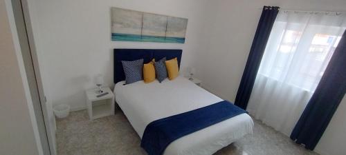 a bedroom with a bed with blue and yellow pillows at Ribeiro´s House in Gafanha da Nazaré