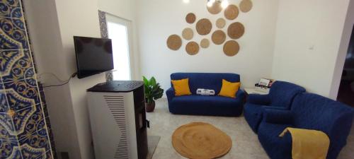 a living room with a blue couch and a tv at Ribeiro´s House in Gafanha da Nazaré