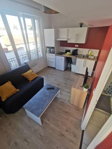 un salon avec un canapé noir et une cuisine dans l'établissement Lumineux T1 de 23m2 à 100m des Métro/Tram, à Villeurbanne