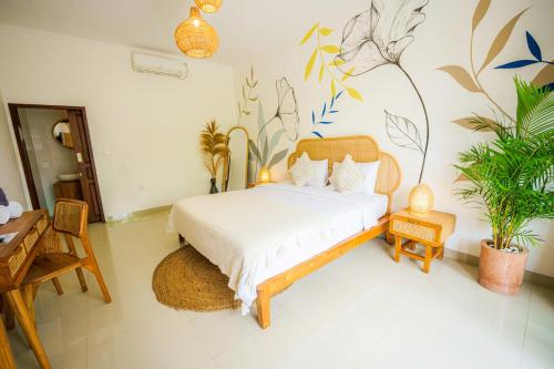 a bedroom with a white bed with plants on the wall at Shortcut Breeze Guest House in Canggu