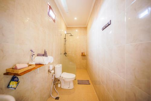 a bathroom with a toilet and a shower at Shortcut Breeze Guest House in Canggu